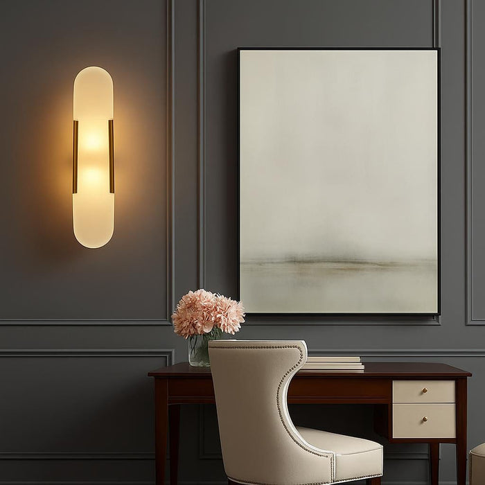A lifestyle scene showing the sconce illuminating a stylish hallway with elegant décor, emphasizing the elongated, rounded silhouette and inviting glow, with a focus on the contrast between the gold finish and the surrounding décor.