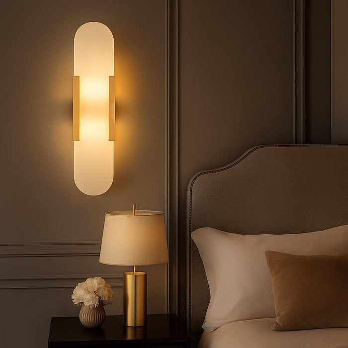 An elegant bedroom setting featuring the Eclipse Wall Sconce beside a bed, casting a warm glow across the space, with a focus on the luxurious brushed gold finish and cozy ambiance.