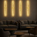 A lifestyle scene showing multiple George Wall Lights installed in a series along a feature wall in a trendy lounge, with warm white glow creating a cozy and sophisticated atmosphere.