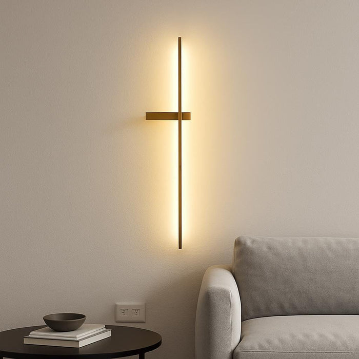 A sleek modern interior with the Dario LED gold wall light mounted on a minimalist white wall, casting a warm ambient glow in a living room setting, emphasizing the luxurious matte gold finish and linear design.