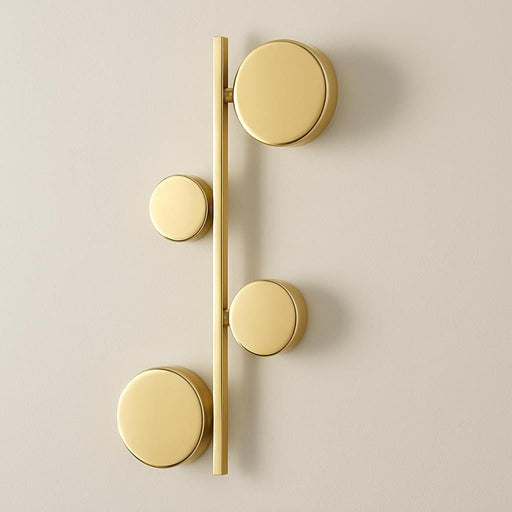 A side view of the Sam Gold Wall Light in a contemporary hallway, emphasizing its linear arrangement of circular elements and the high-quality aluminum construction, with a neutral, sophisticated backdrop.