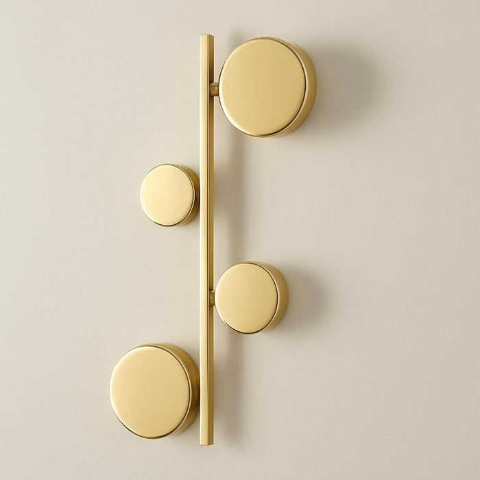 A side view of the Sam Gold Wall Light in a contemporary hallway, emphasizing its linear arrangement of circular elements and the high-quality aluminum construction, with a neutral, sophisticated backdrop.